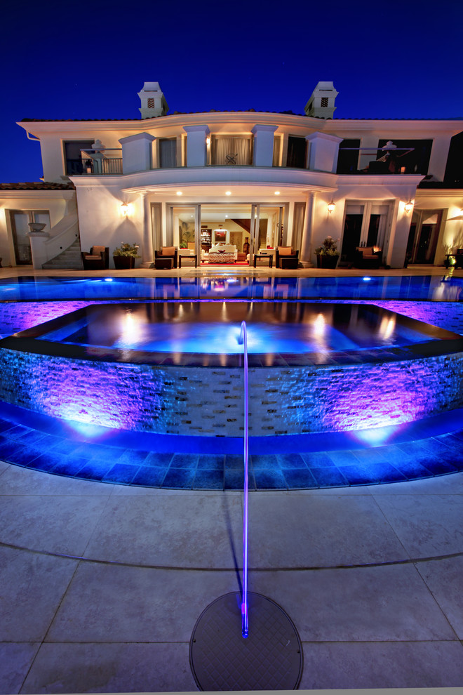 Foto på en stor funkis infinitypool på baksidan av huset, med en fontän och naturstensplattor