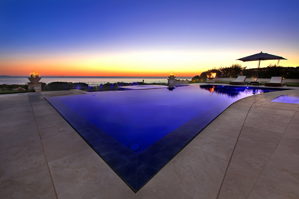Immagine di una grande piscina a sfioro infinito contemporanea personalizzata dietro casa con fontane e pavimentazioni in pietra naturale