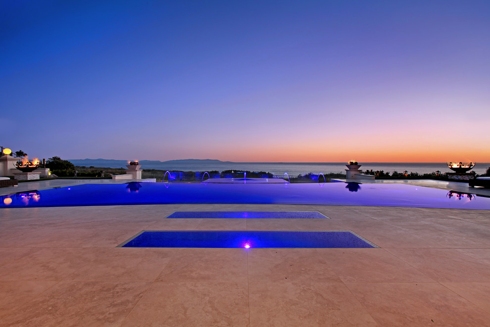 Ejemplo de piscina con fuente infinita contemporánea grande a medida en patio trasero con adoquines de piedra natural