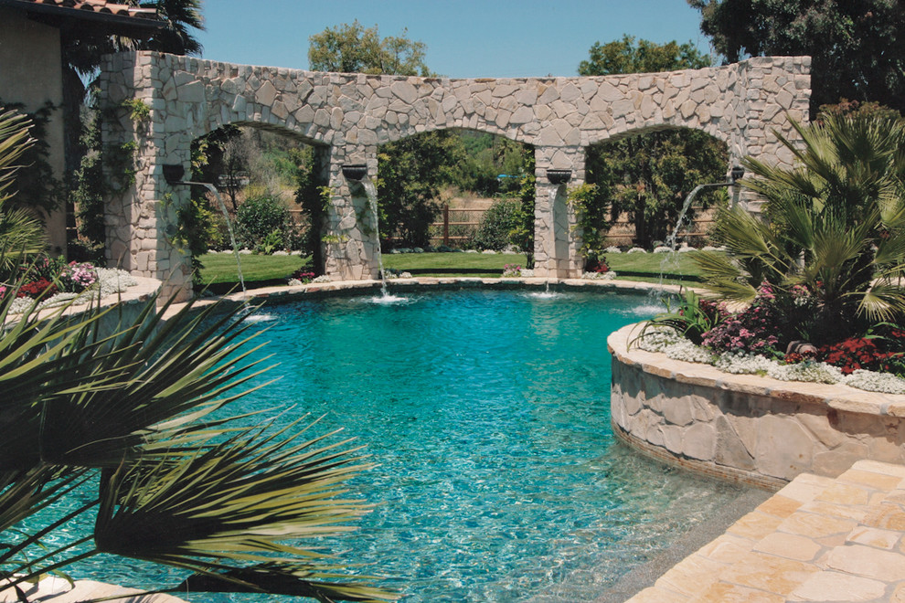Diseño de piscina con fuente clásica a medida con adoquines de piedra natural