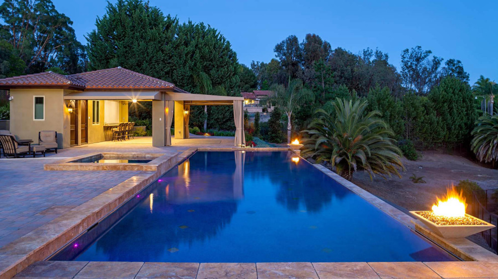 Large tuscan backyard tile and rectangular infinity pool house photo in San Diego