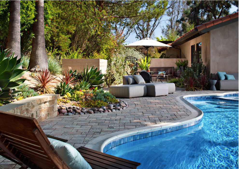 На фото: бассейн среднего размера, в форме фасоли на заднем дворе в средиземноморском стиле с мощением тротуарной плиткой с