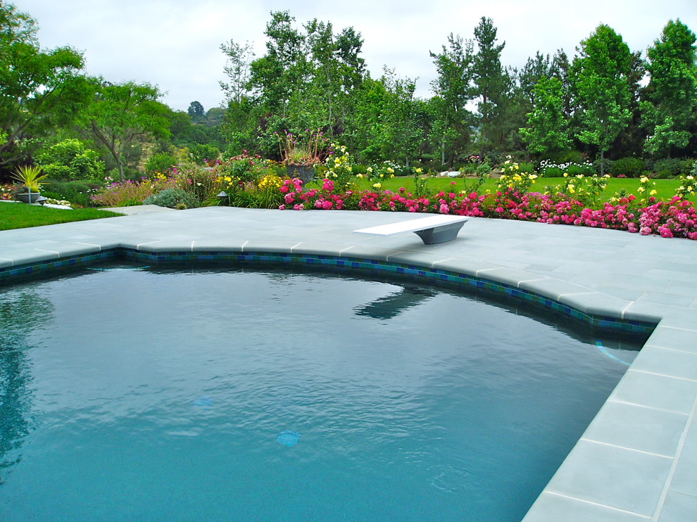 Inspiration pour une grande piscine arrière traditionnelle avec un bain bouillonnant et des pavés en béton.