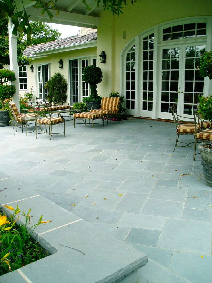 Idée de décoration pour une terrasse arrière tradition avec des pavés en pierre naturelle.