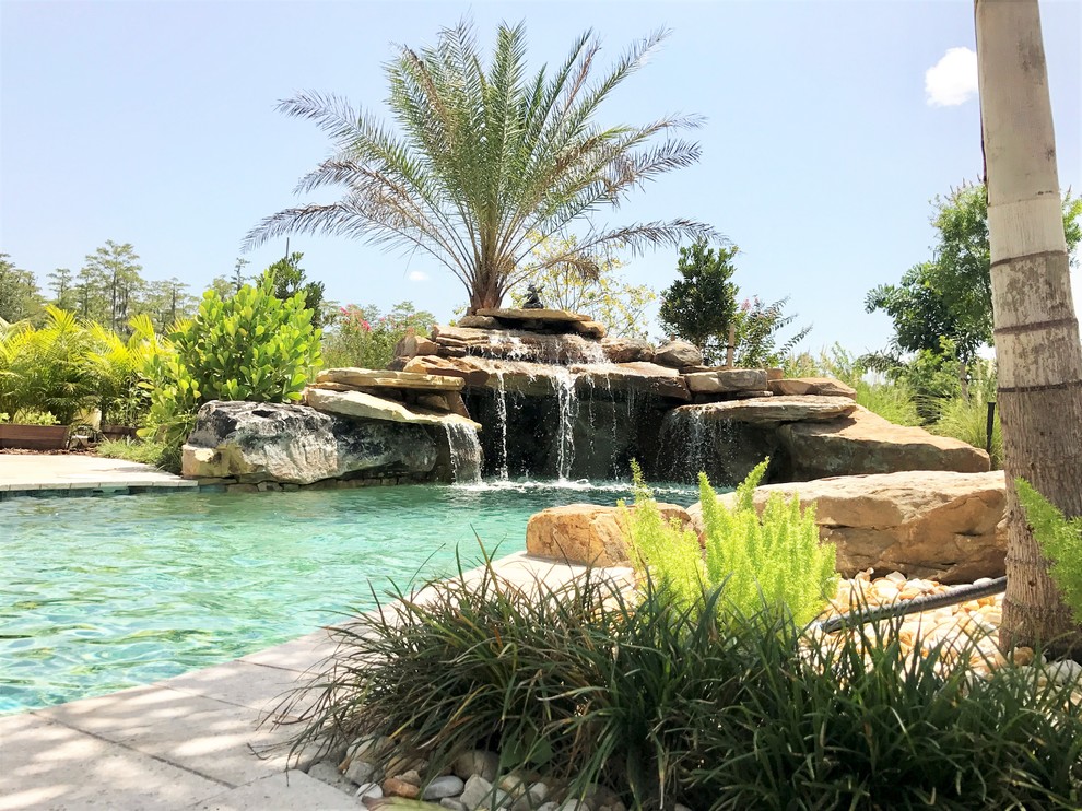 Inspiration for a large world-inspired back custom shaped natural swimming pool in Orlando with a water feature and natural stone paving.