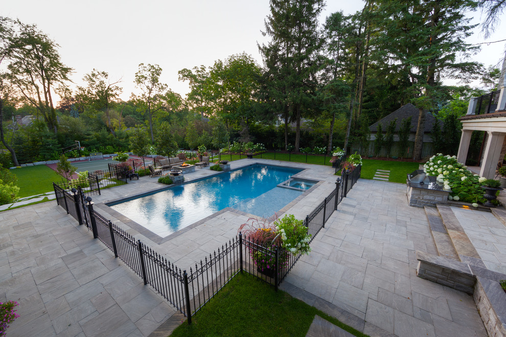 Großer Klassischer Pool hinter dem Haus in rechteckiger Form mit Wasserspiel und Natursteinplatten in Sonstige
