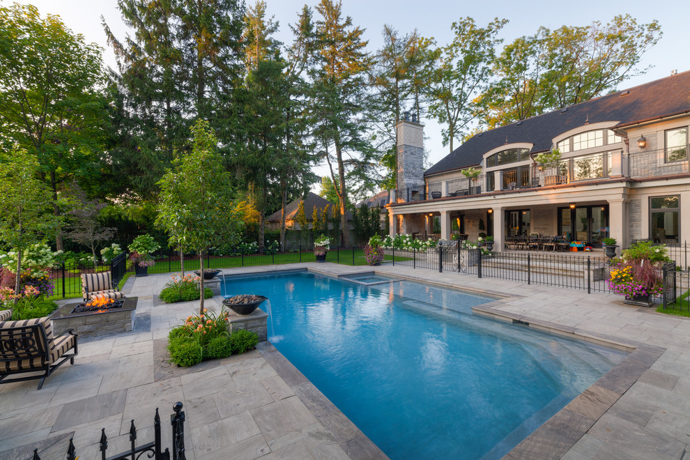 Großer Klassischer Pool hinter dem Haus in rechteckiger Form mit Wasserspiel und Natursteinplatten in Sonstige