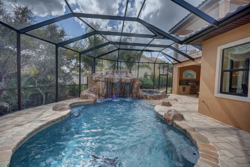 Großer Mediterraner Schwimmteich hinter dem Haus in individueller Form mit Wasserspiel und Natursteinplatten in Orlando