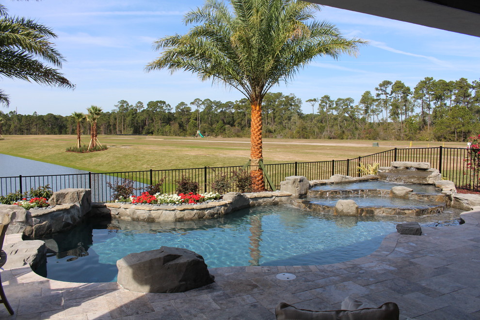 Ispirazione per una piscina tropicale personalizzata dietro casa con fontane e pavimentazioni in pietra naturale