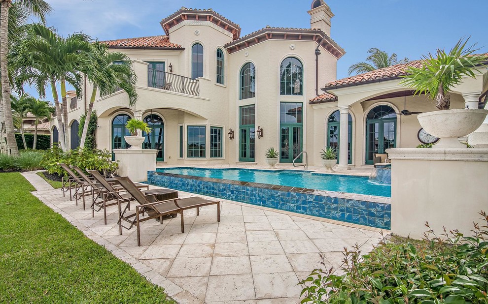Mediterranean swimming pool in Miami with a water feature and tiled flooring.