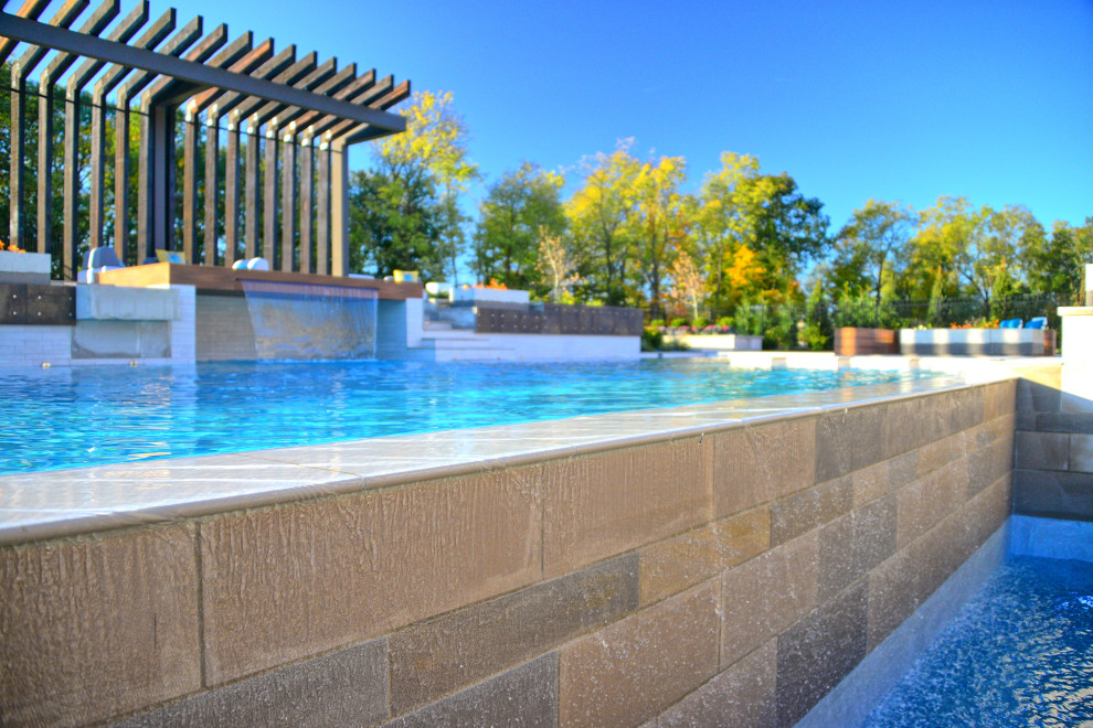 Foto di un'ampia piscina moderna rettangolare dietro casa con una vasca idromassaggio e piastrelle