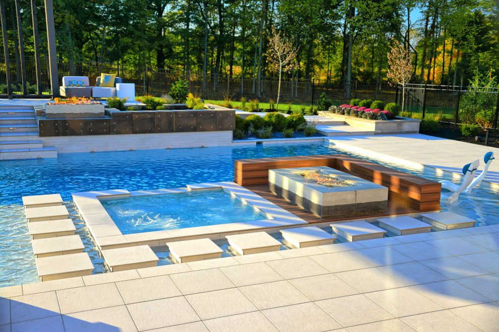 Foto på en mycket stor funkis pool på baksidan av huset, med spabad och kakelplattor