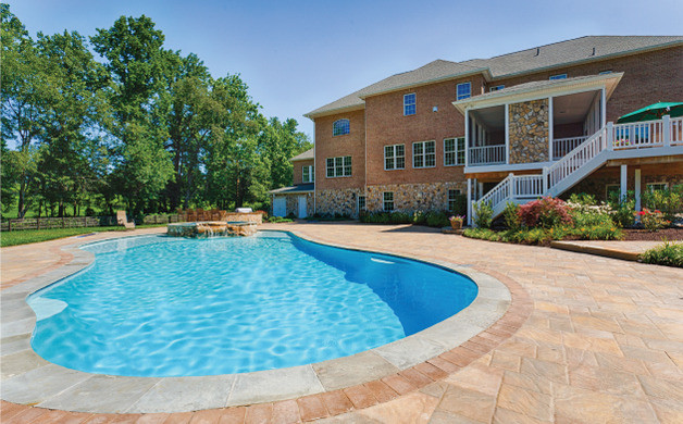 Ispirazione per una grande piscina naturale classica personalizzata dietro casa con pavimentazioni in cemento e una vasca idromassaggio