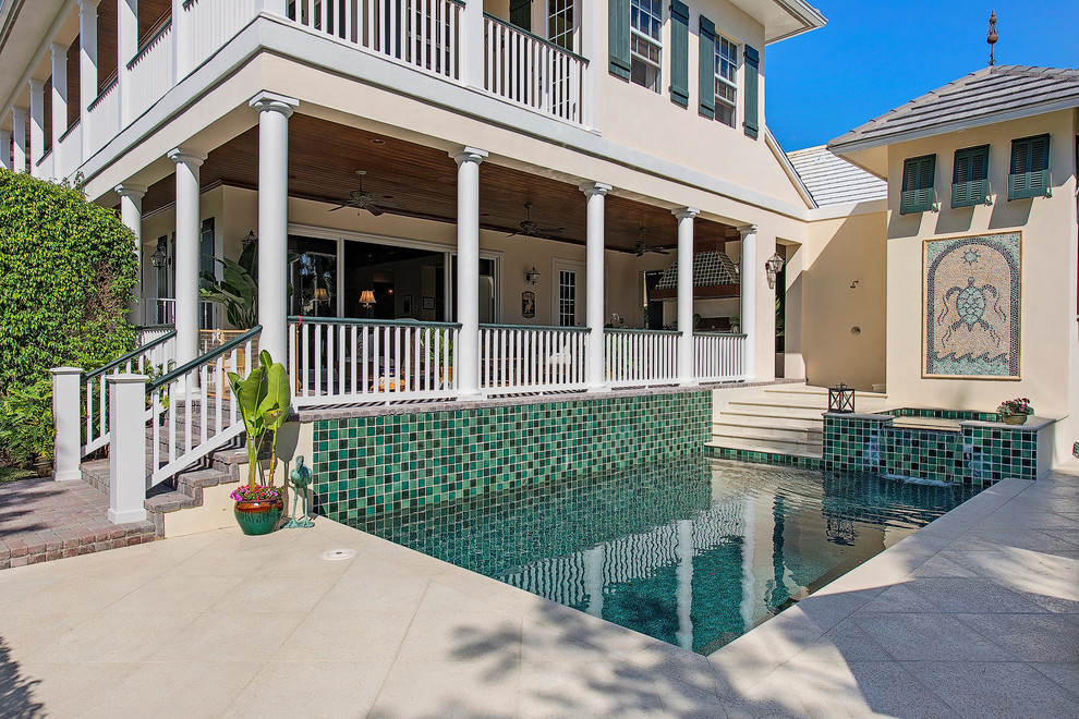 Immagine di una piscina tropicale rettangolare dietro casa con fontane e piastrelle