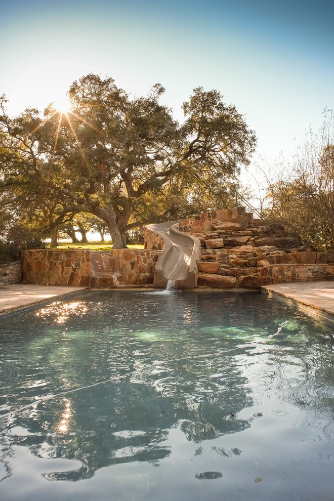 This is an example of a rustic rectangular swimming pool in Austin with a water slide.