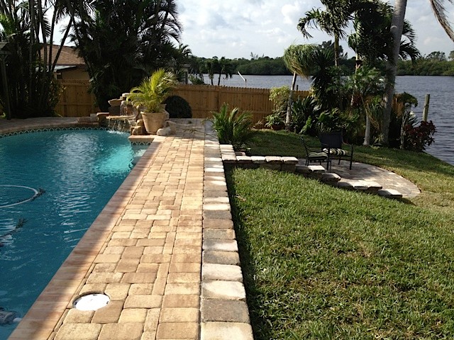 Modelo de piscina con fuente alargada exótica de tamaño medio rectangular en patio trasero con adoquines de ladrillo