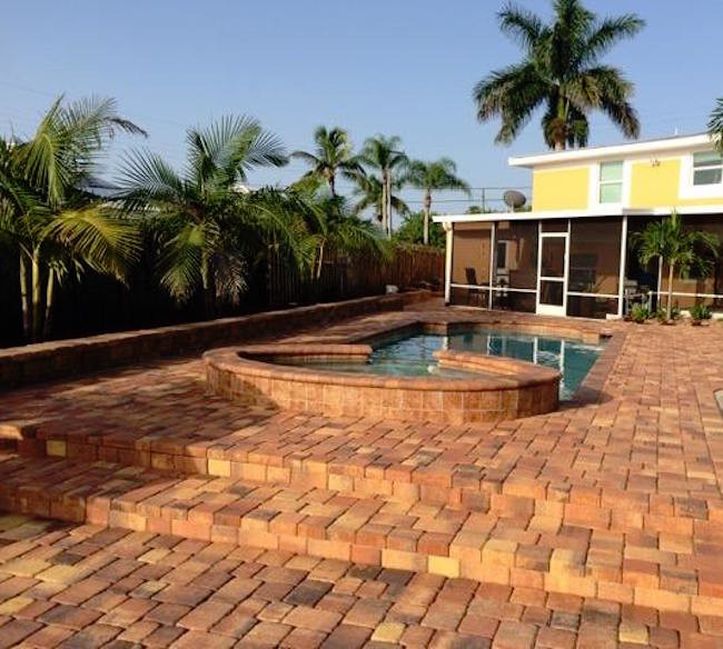 Großer Pool hinter dem Haus in rechteckiger Form mit Pflastersteinen in Miami