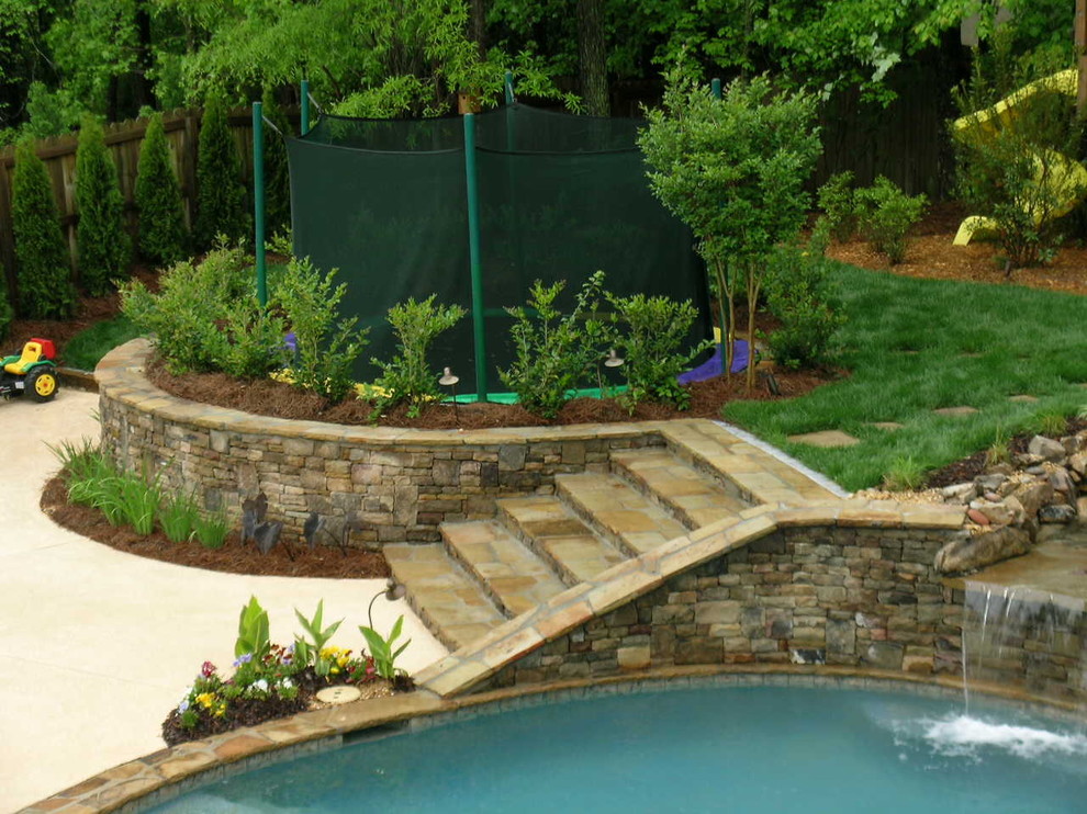 Diseño de piscina con fuente natural tradicional grande a medida en patio trasero con adoquines de piedra natural