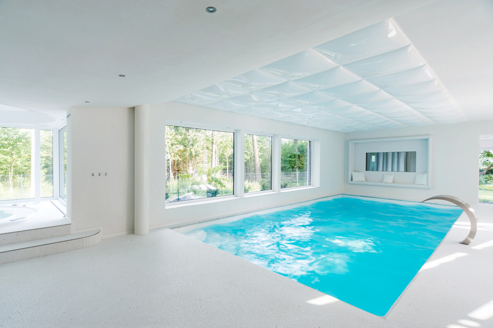 Mittelgroßer Moderner Indoor-Pool in rechteckiger Form mit Wasserspiel und Betonboden in Nürnberg