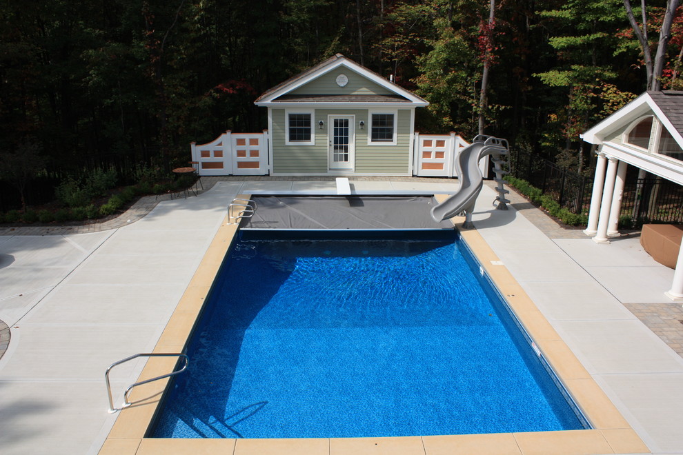 Ispirazione per una grande piscina monocorsia chic rettangolare dietro casa con un acquascivolo e lastre di cemento