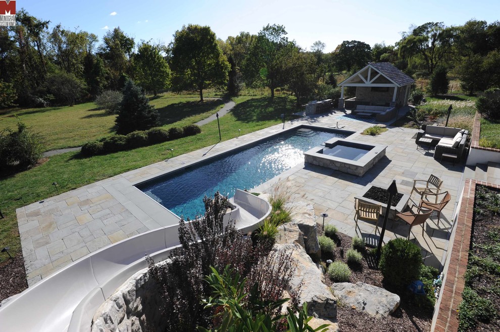 Modelo de piscina con tobogán alargada contemporánea grande rectangular en patio trasero