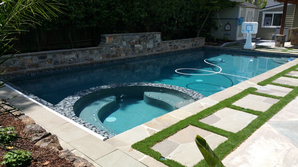 Imagen de piscina con fuente alargada tradicional renovada de tamaño medio rectangular en patio trasero con adoquines de piedra natural