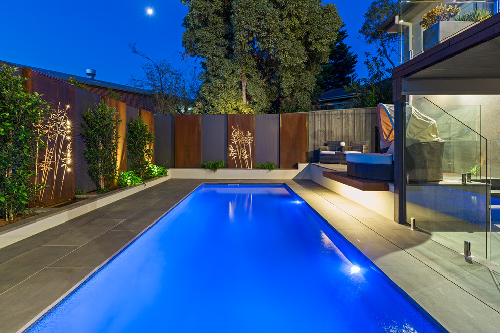 Immagine di una piccola piscina naturale minimalista rettangolare dietro casa con fontane e pavimentazioni in pietra naturale