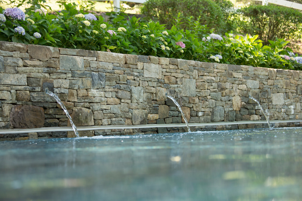 Immagine di una piscina tradizionale rettangolare di medie dimensioni e dietro casa con fontane