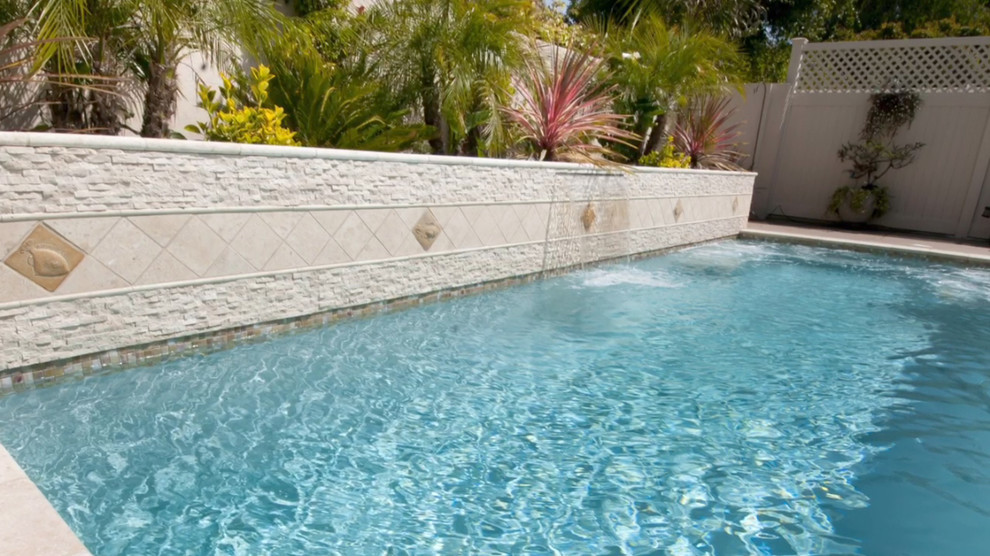 Modelo de piscina mediterránea pequeña rectangular en patio trasero con losas de hormigón