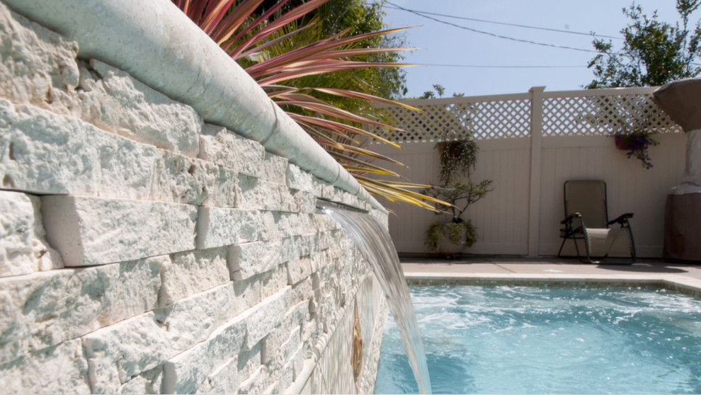 Ejemplo de piscina mediterránea pequeña rectangular en patio trasero con losas de hormigón