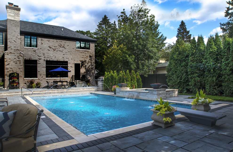 Idee per una piscina chic rettangolare di medie dimensioni e dietro casa con una vasca idromassaggio e pavimentazioni in pietra naturale