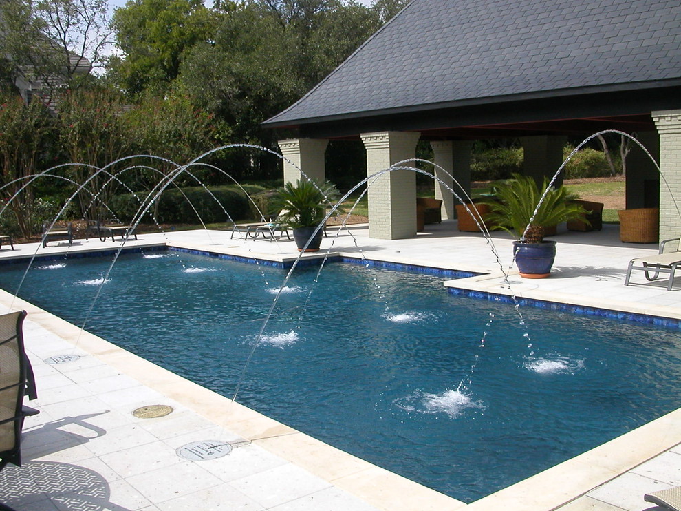 This is an example of a large traditional back rectangular lengths swimming pool in Dallas with a water feature and tiled flooring.