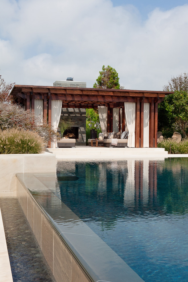 Ejemplo de piscinas y jacuzzis infinitos minimalistas de tamaño medio rectangulares en patio trasero con adoquines de piedra natural