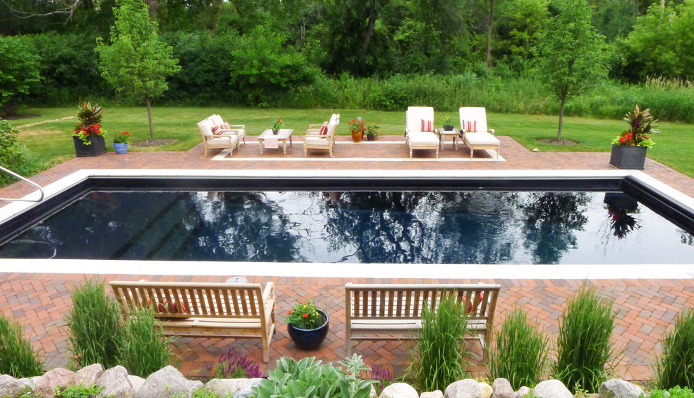 Diseño de piscina campestre de tamaño medio rectangular en patio trasero con adoquines de ladrillo