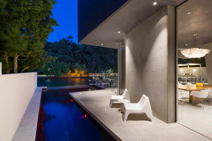 Foto de piscina alargada contemporánea de tamaño medio en forma de L en patio lateral con adoquines de hormigón
