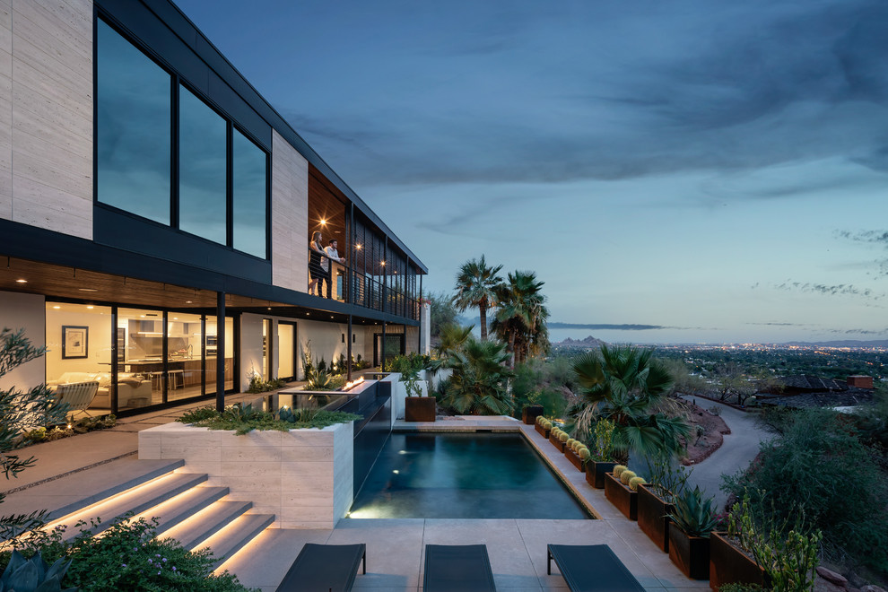Idee per una grande piscina a sfioro infinito design rettangolare davanti casa con lastre di cemento