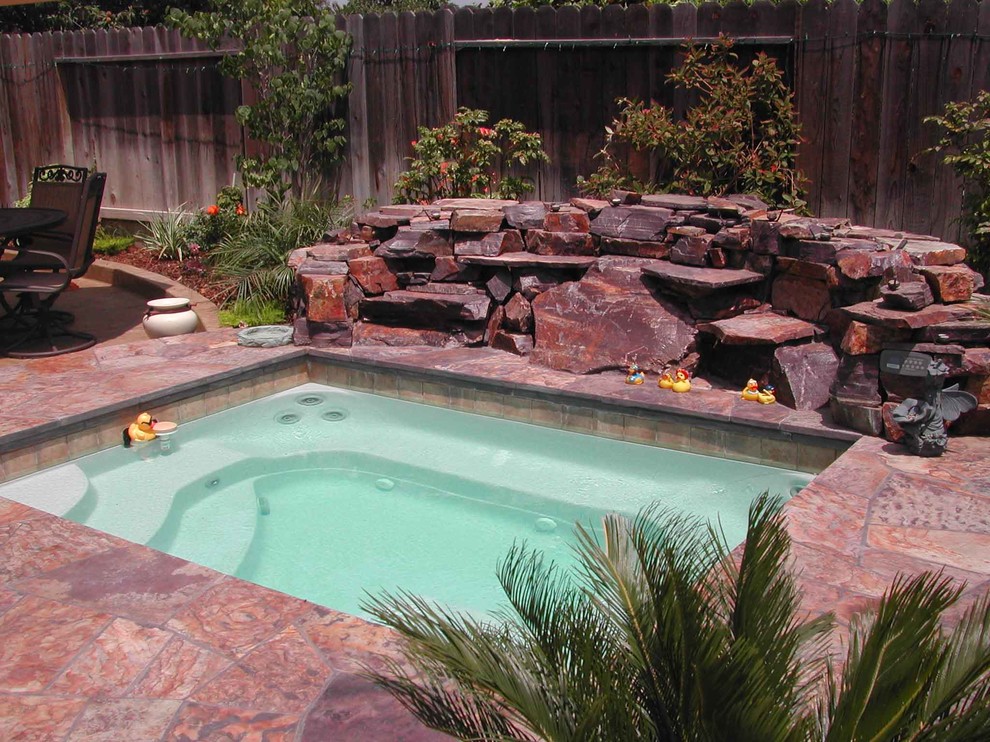 Ispirazione per una piscina naturale tradizionale rettangolare di medie dimensioni e dietro casa con una vasca idromassaggio e pavimentazioni in pietra naturale