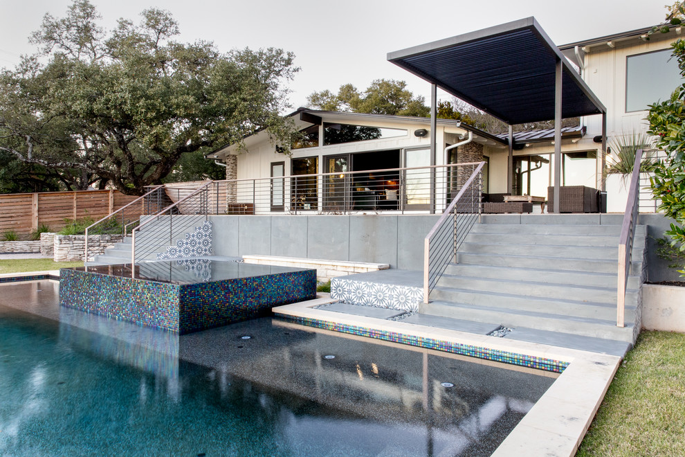 Ispirazione per una piscina a sfioro infinito contemporanea personalizzata di medie dimensioni e dietro casa con una vasca idromassaggio e pavimentazioni in cemento