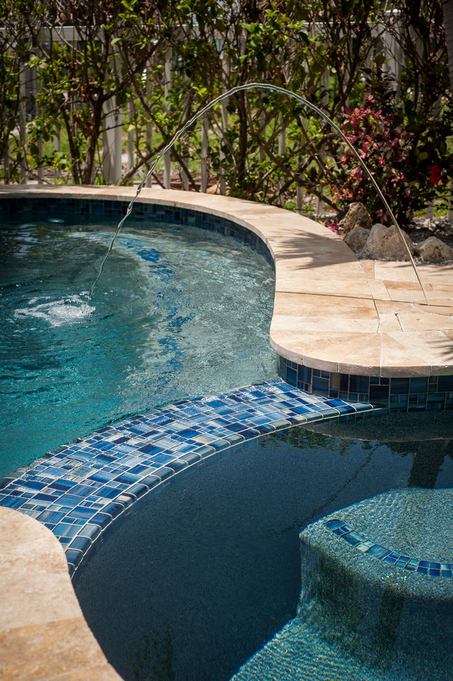 Diseño de piscinas y jacuzzis tropicales de tamaño medio a medida en patio trasero con adoquines de piedra natural