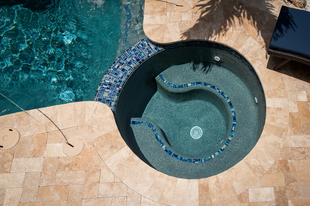 Modelo de piscinas y jacuzzis exóticos de tamaño medio a medida en patio trasero con adoquines de piedra natural