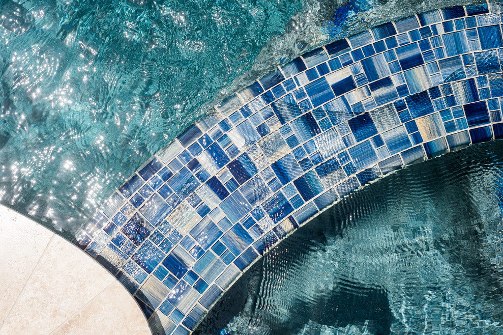 Immagine di una piscina tropicale personalizzata di medie dimensioni e dietro casa con una vasca idromassaggio e pavimentazioni in pietra naturale