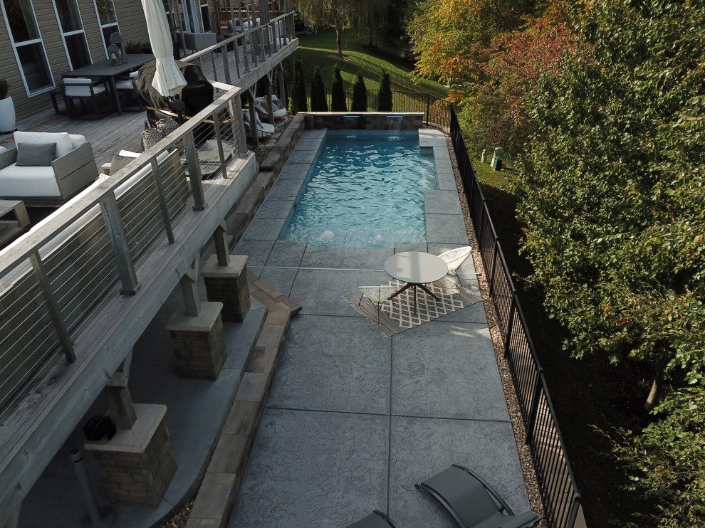 Inspiration for a large modern back rectangular natural swimming pool in St Louis with with pool landscaping and stamped concrete.