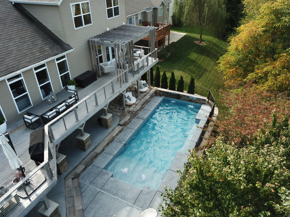 Diseño de piscina natural minimalista grande rectangular en patio trasero con paisajismo de piscina y suelo de hormigón estampado