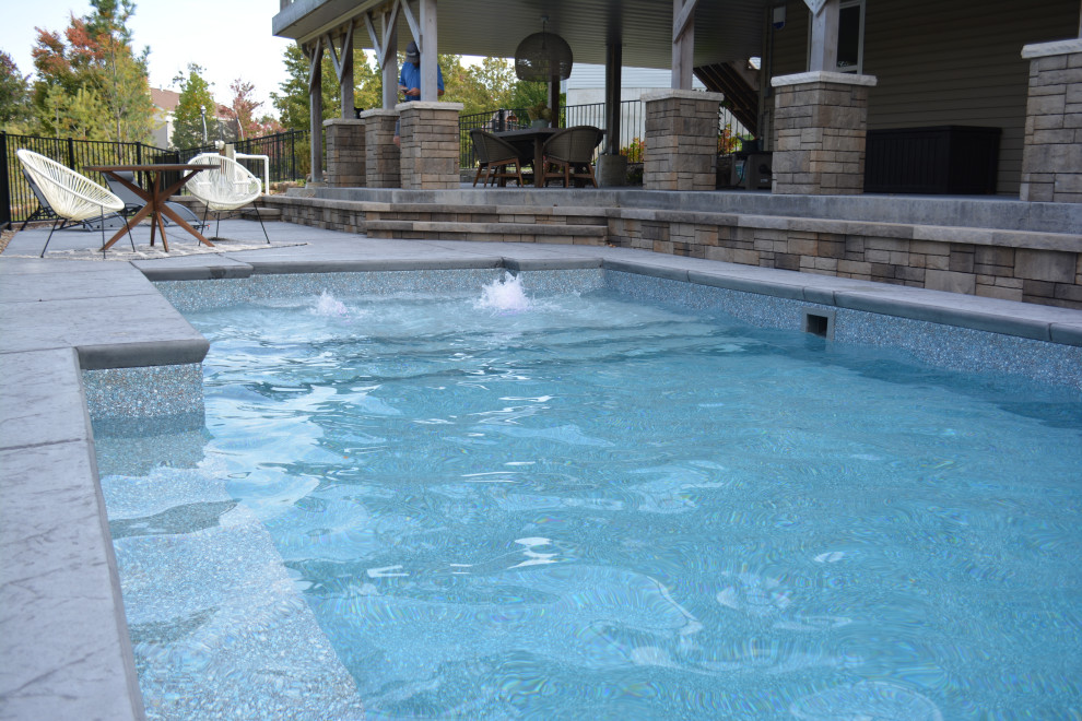 Cette photo montre un grand piscine avec aménagement paysager arrière moderne rectangle avec du béton estampé.