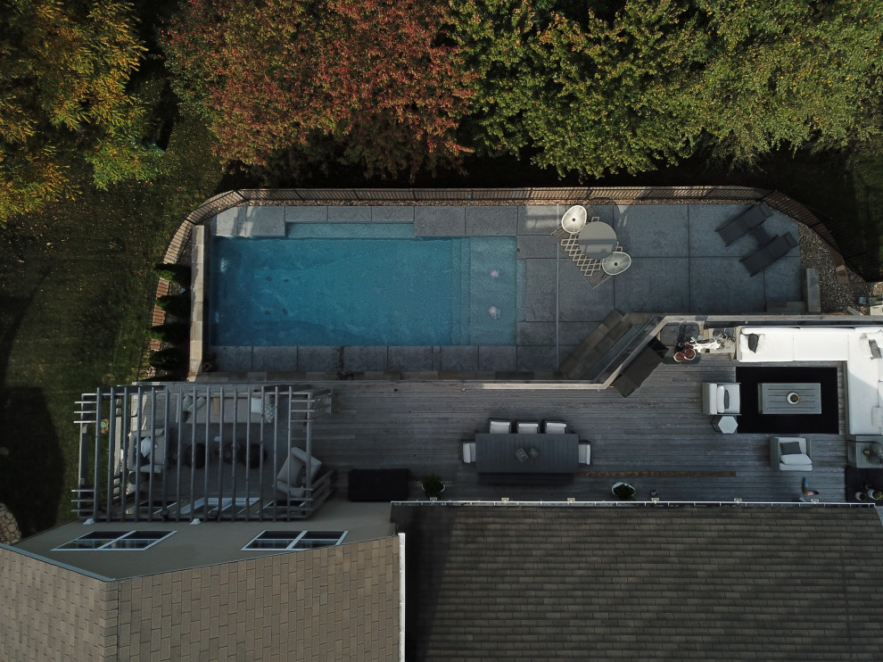 Réalisation d'un grand piscine avec aménagement paysager arrière minimaliste rectangle avec du béton estampé.