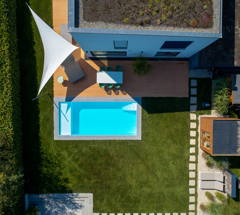 Modelo de piscina moderna de tamaño medio rectangular en patio lateral con losas de hormigón