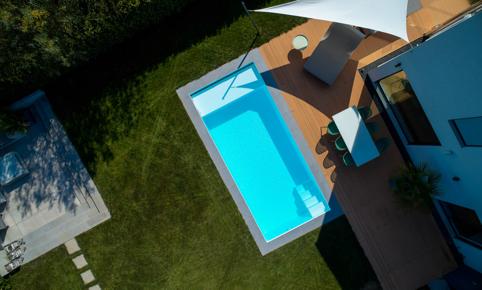 Ejemplo de piscina minimalista de tamaño medio rectangular en patio lateral con losas de hormigón