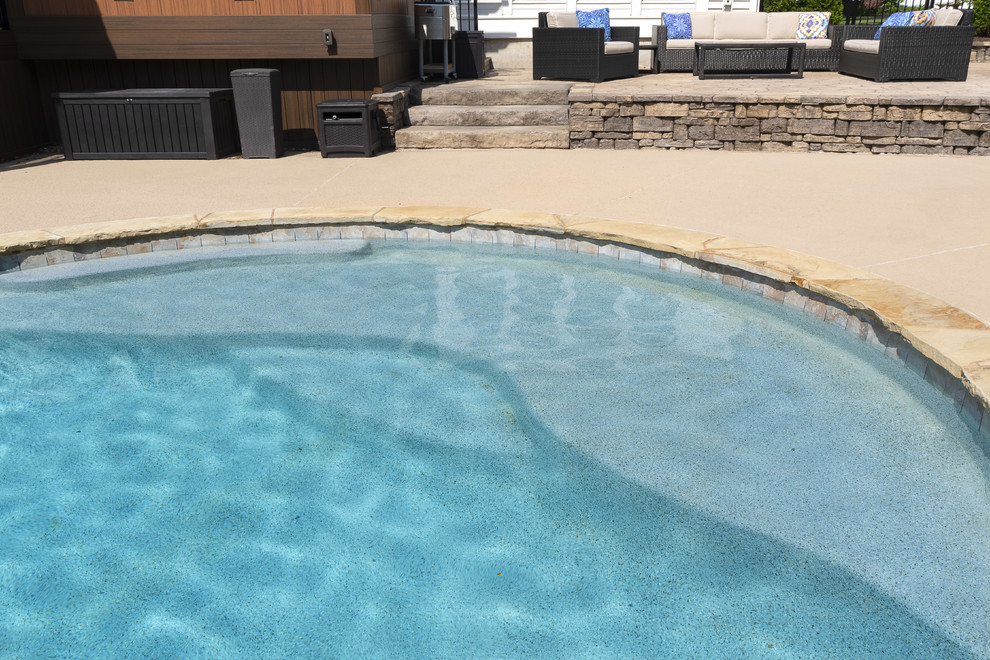Inspiration for a large classic back custom shaped natural swimming pool in St Louis with a water feature and natural stone paving.