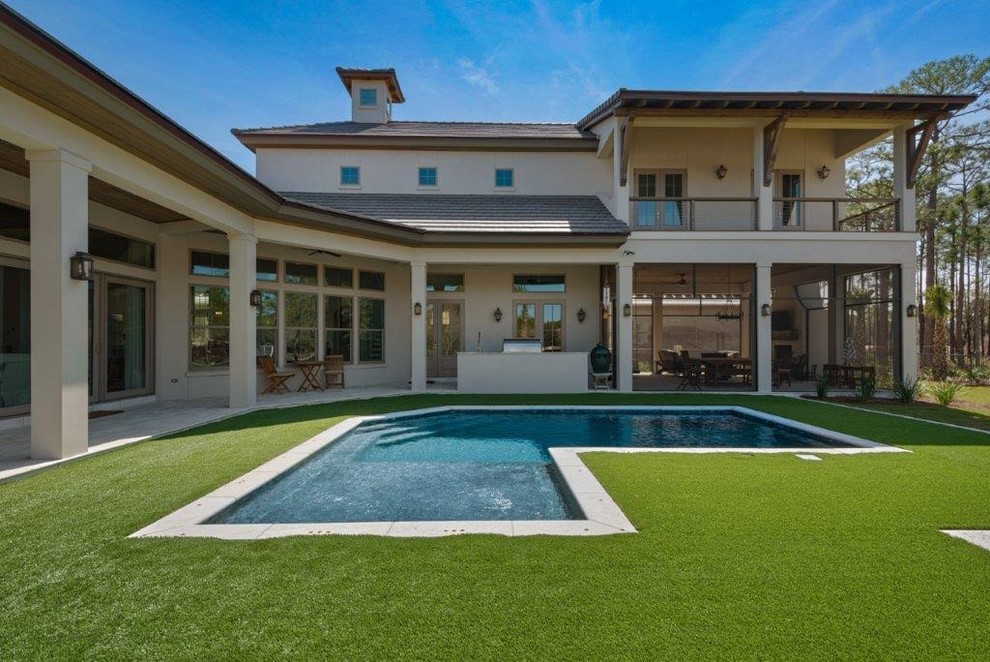 Idee per una grande piscina a sfioro infinito chic a "L" dietro casa con pavimentazioni in cemento