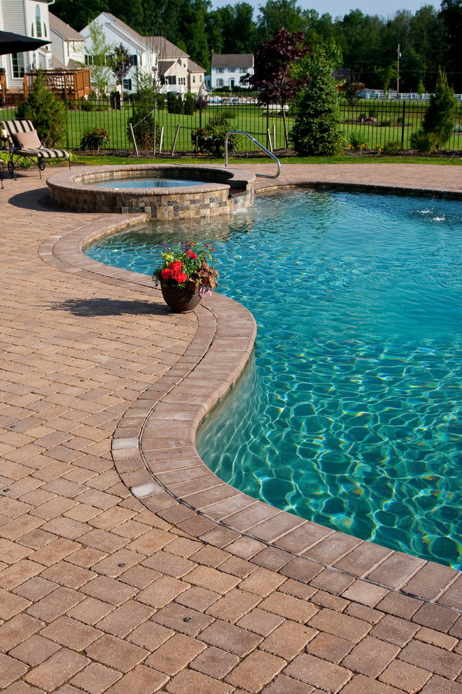 Foto de piscinas y jacuzzis tradicionales grandes a medida en patio trasero con adoquines de piedra natural